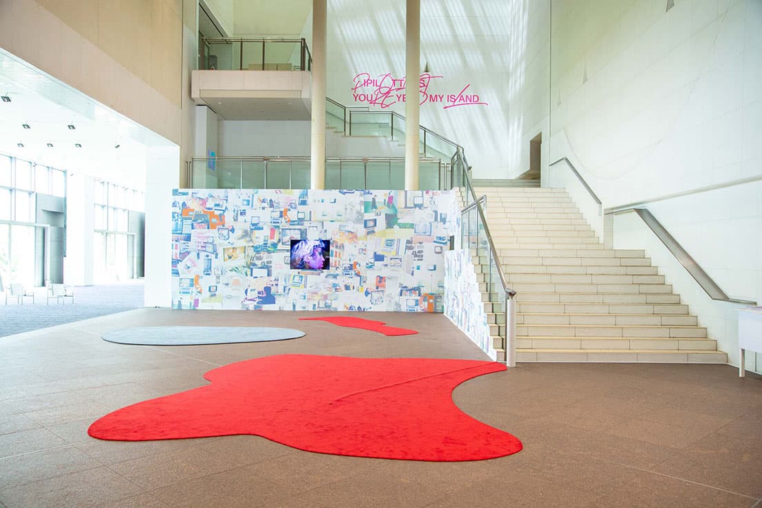 『ピピロッティ・リスト：Your Eye Is My Island －あなたの眼はわたしの島－』展、ロビーでの展示風景。島のようなカーペットが出迎える。