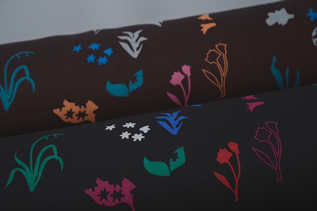 《“dancing flora” （上／dark brown 下／black）》リネン100％　9,350円／m　自由に動き回る野原の小さな草花たち。月夜のスポットライトを浴びながらダンスをしているかのよう。