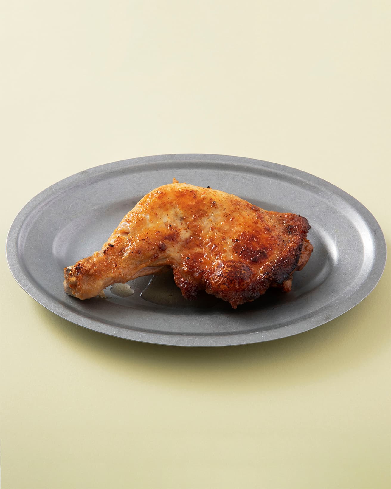 お皿に骨付鳥を盛り付けたら、フライパンに残ったチキンオイルをかけて完成。チキンオイルは別売。