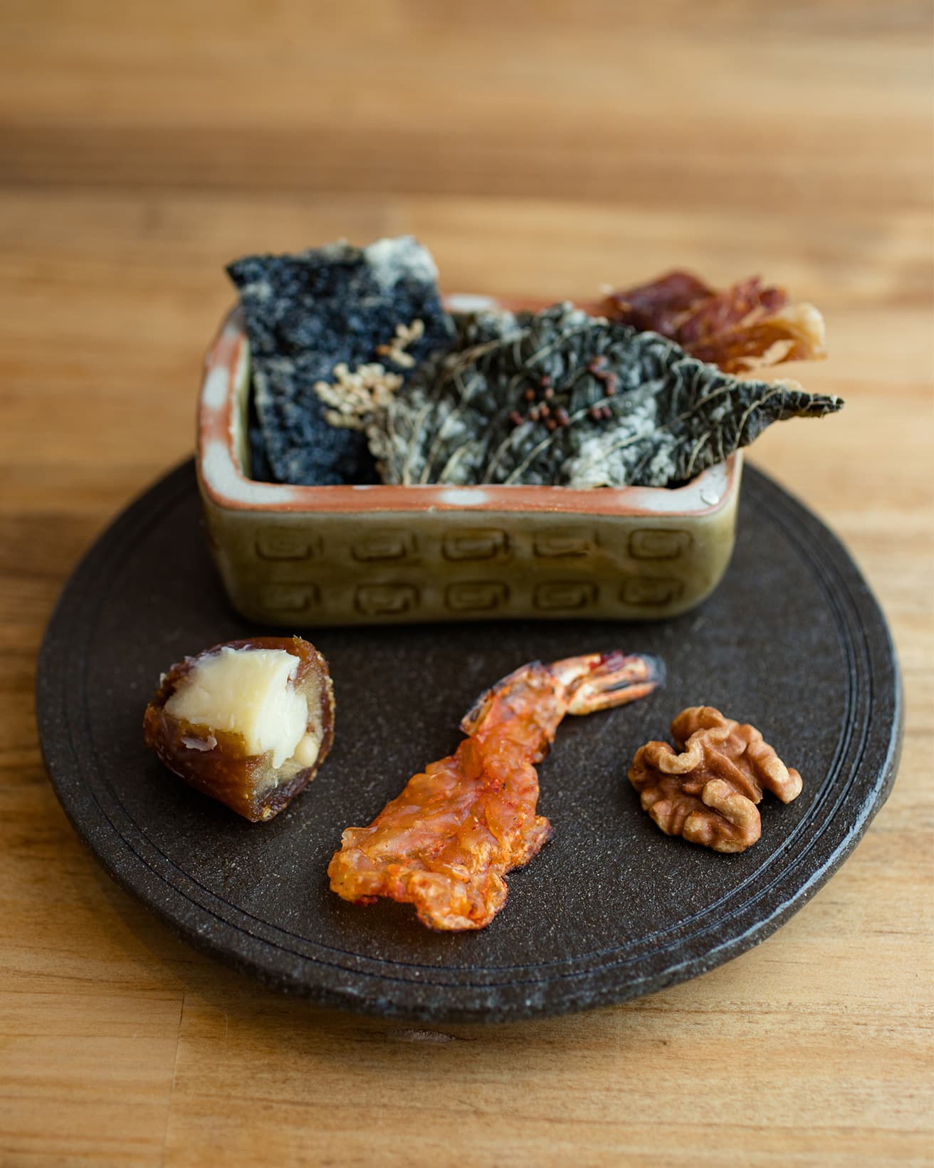 アミューズ「自家製韓国伝統薬脯（ヤクポ）ビーフジャーキー、海苔の餅糊衣揚げ、エゴマの葉の餅糊衣揚げ、胡桃のじっくり揚げ、エビのジャーキーをサッと炙って、棗椰子にクリーム・チーズと松の実」。お酒が進む大人気の一品。