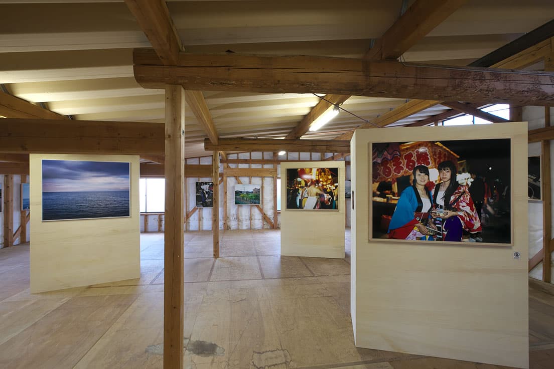 石川直樹《奥能登半島／珠洲全景》展示風景。キリコ祭りや「あえのこと」などをとらえた写真が並ぶ。　photo_Kichirō Okamura