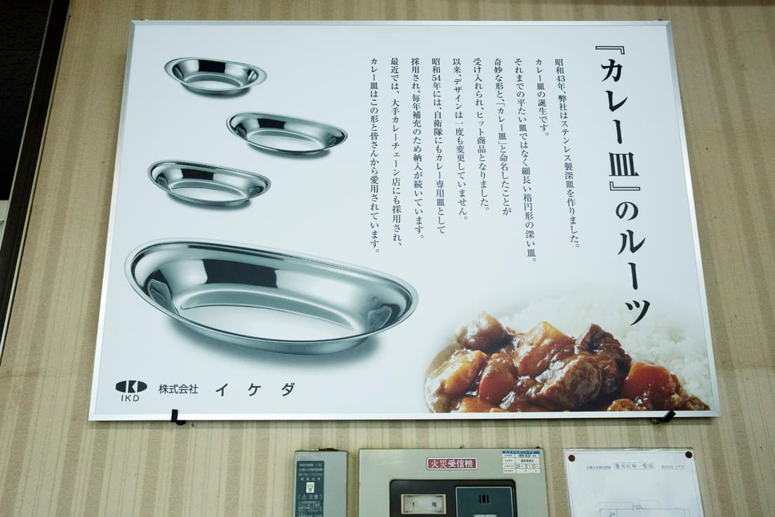 工場内には、カレー皿の誕生ストーリーが記されたポスターが。50年続くロングセラーの誇りが感じられる。