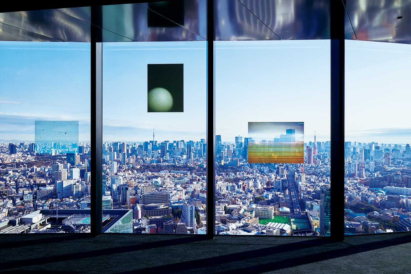 透明のフィルムに印刷された写真と、透けて見える都市の風景が混じり合う。