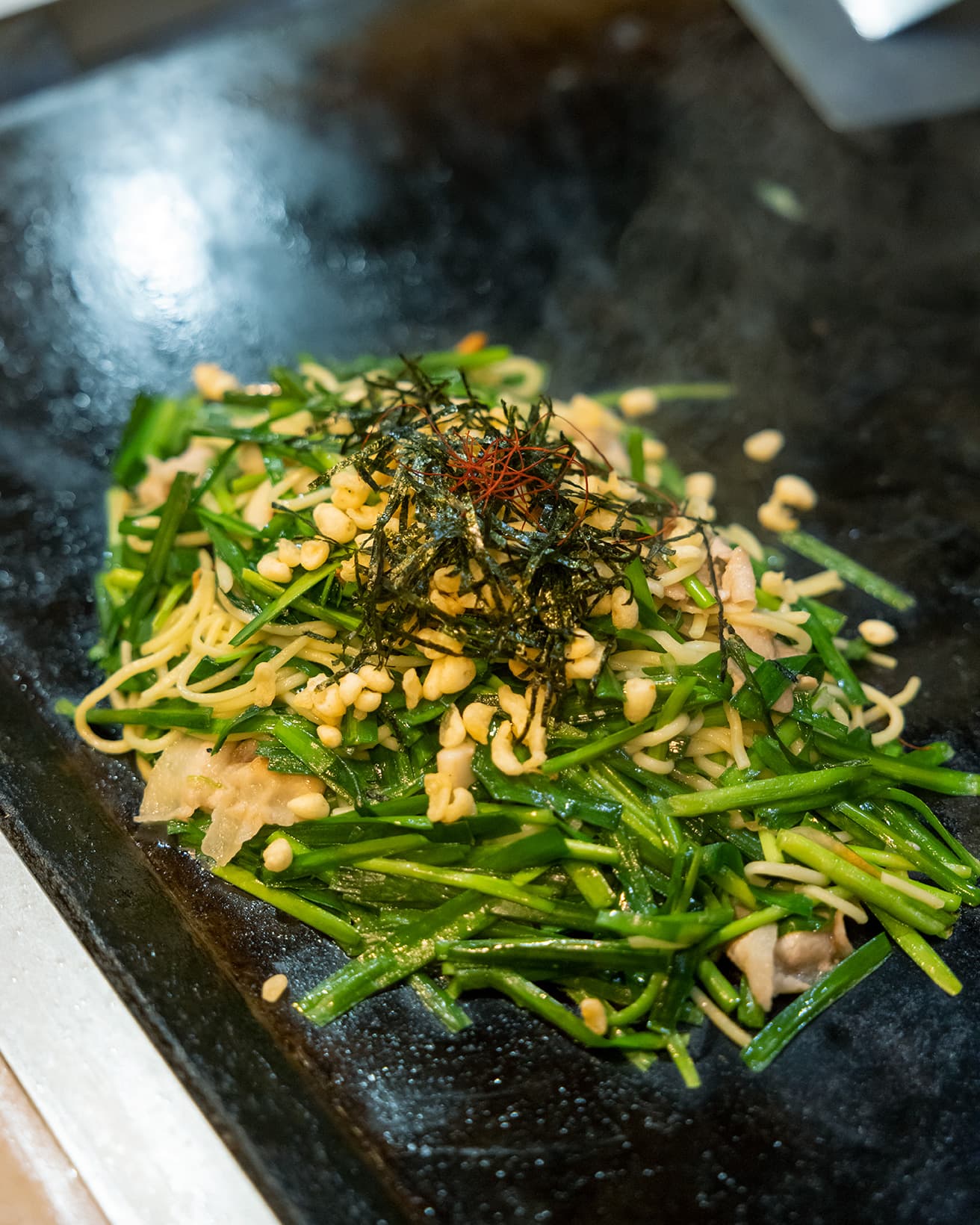 鉄板の上で焼き上げられた「ニラ塩焼きそば」700円。仕上げに揚げ玉、きざみのり、糸唐辛子をトッピング。
