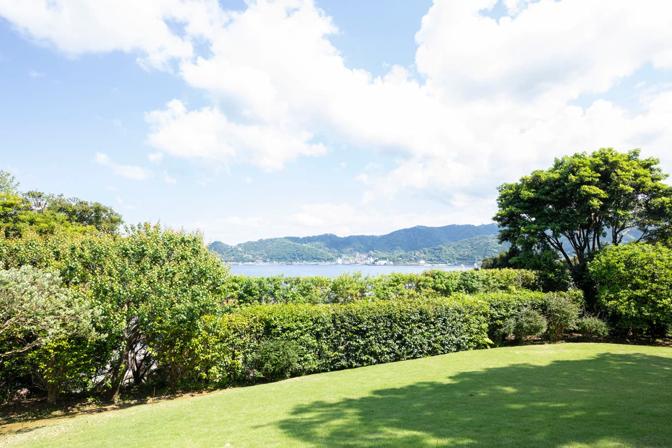 青々とした芝生と、自然の風合いを大切にしながら刈り込まれた樹木ごしに海が見える。