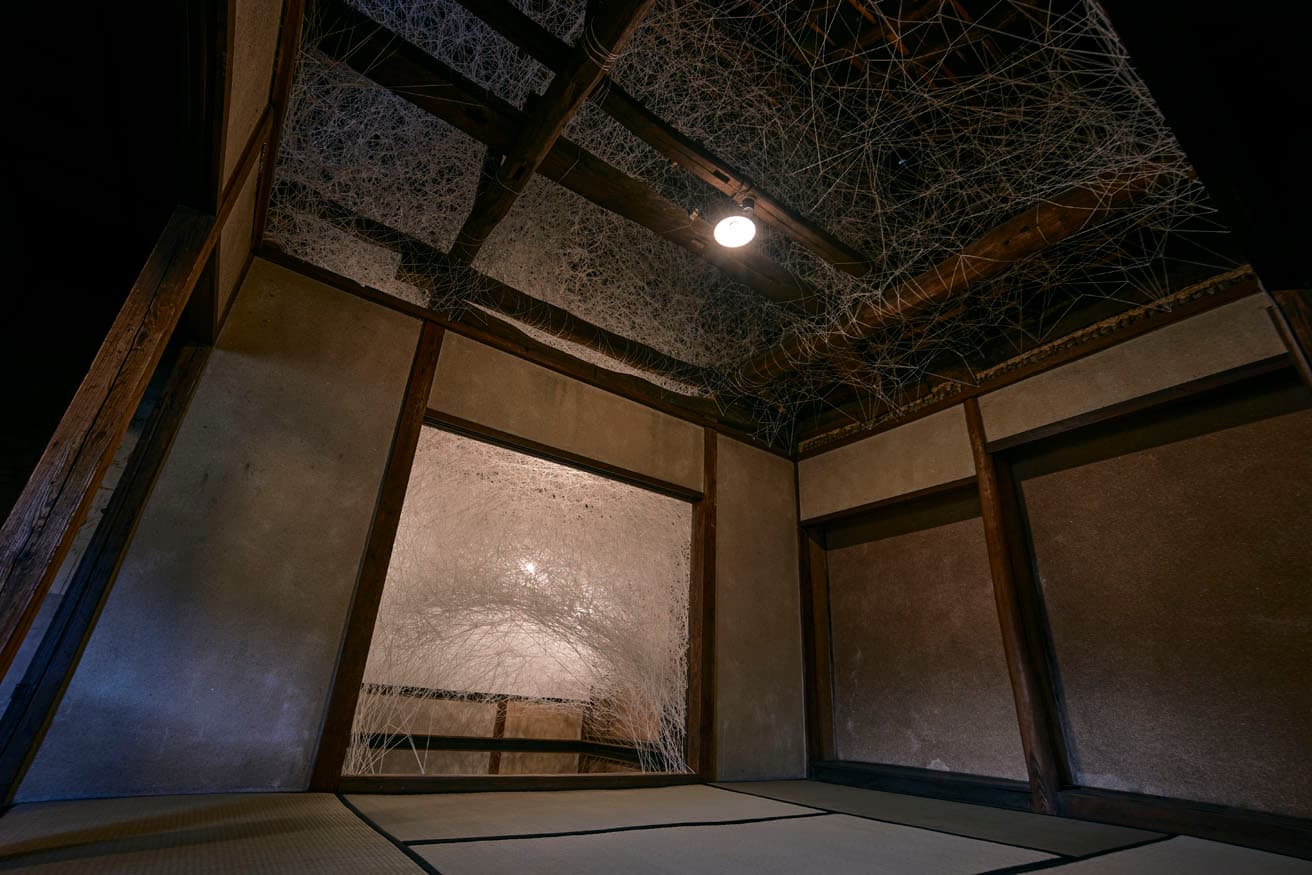 《巡る記憶 ― 草本商店》。梁の上にも白い糸が張り巡らされている。白は湯けむりからストレートに着想されたものだそう。
