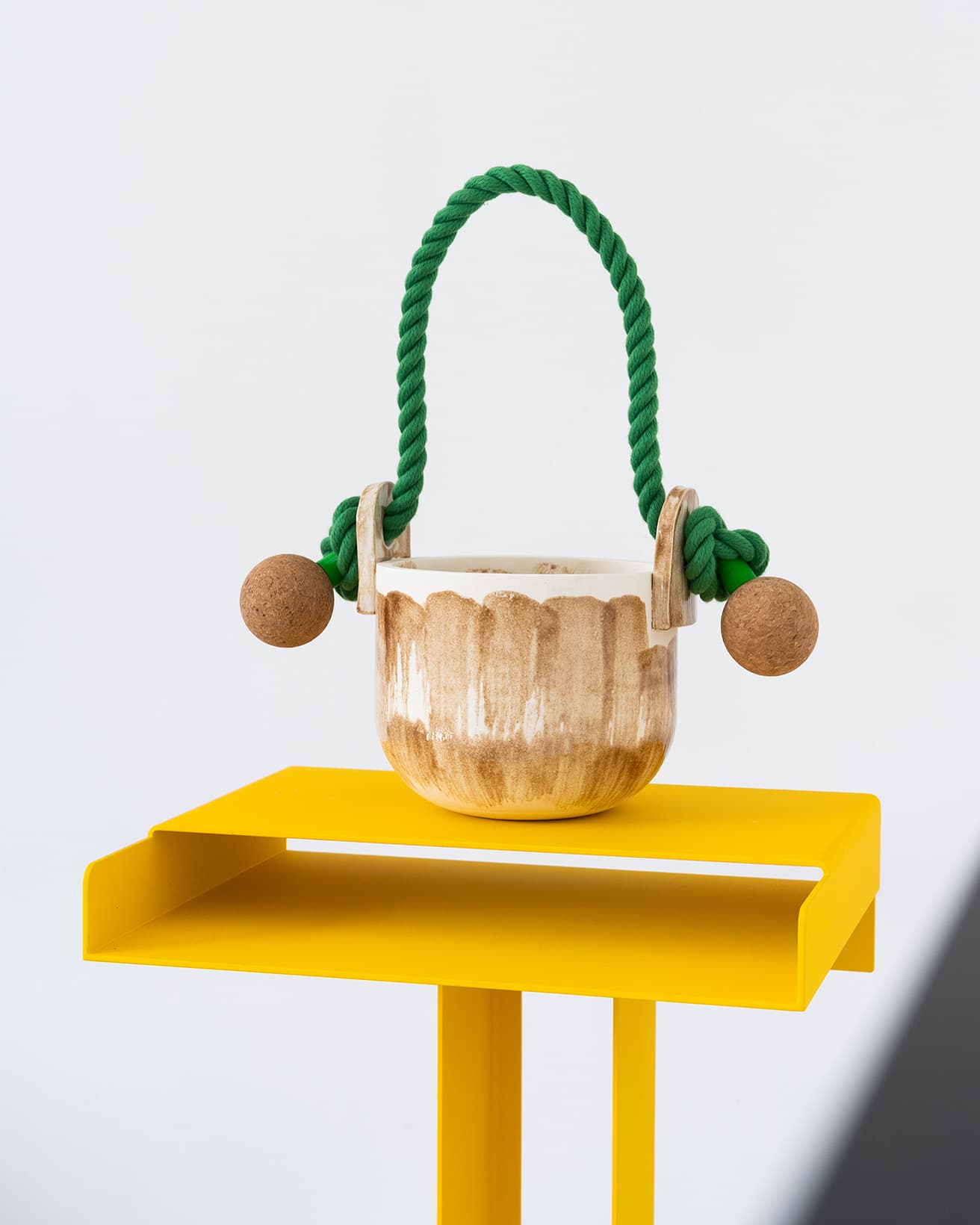 もともとカメラストラップにルーツを持つカバン作りで人気を博した〈トシキ〉らしい、ユニークな持ち手を持つ陶芸作品。台座となっているのは〈ニューテンデンシー〉のサイドテーブル。