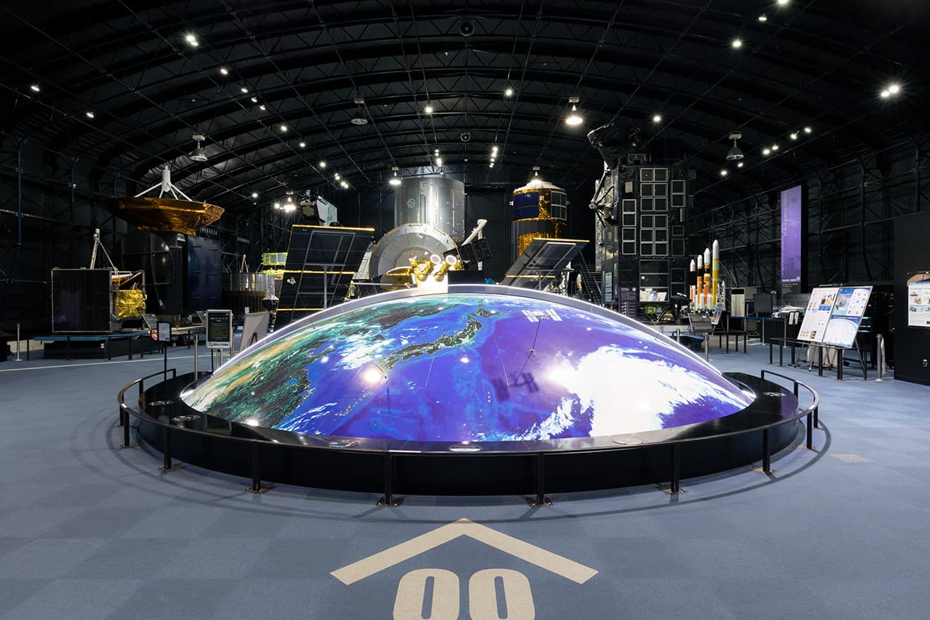 100万分の1サイズの地球「ドリームポート」。
青い惑星の上空には、JAXAが運用中の人工衛星や国際宇宙ステーションの軌道が描かれている。