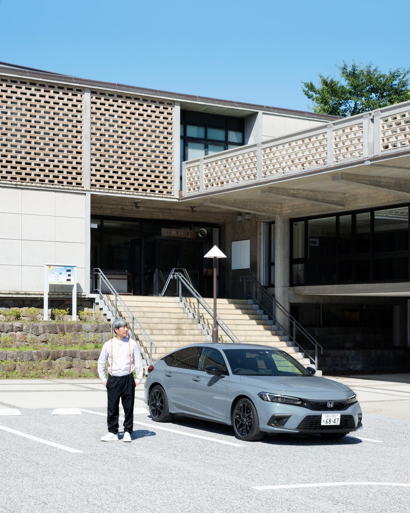 〈神奈川県立図書館 前川國男館〉前の《CIVIC e:HEV》と幅允孝。ホローブリックの外観とボディカラーのソニックグレー・パールの調和が美しい。