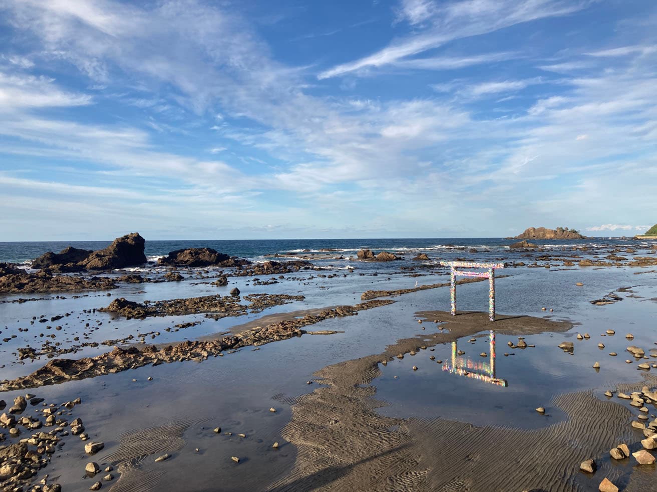ファイグ・アフメッド《自身への扉》は岸辺の海に立つ鳥居。陽の光を浴びて海と一緒に輝く。
