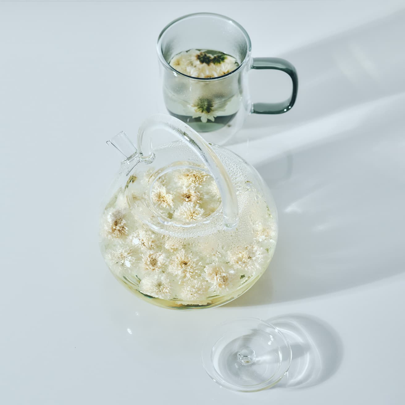 中国茶愛好家たち御用達ブランド〈ポカロティー〉の《透明丸型ティーポット》は、茶こし付き、直火対応の優れもの。茶葉がゆったりとジャンピングできる丸型で、飽きのこないシンプルなデザインは長く使うほどに愛着が湧く。〈ニュイ〉の耐熱二層ガラスのガラスマグは、シックな薄いグレーがアクセントに。
