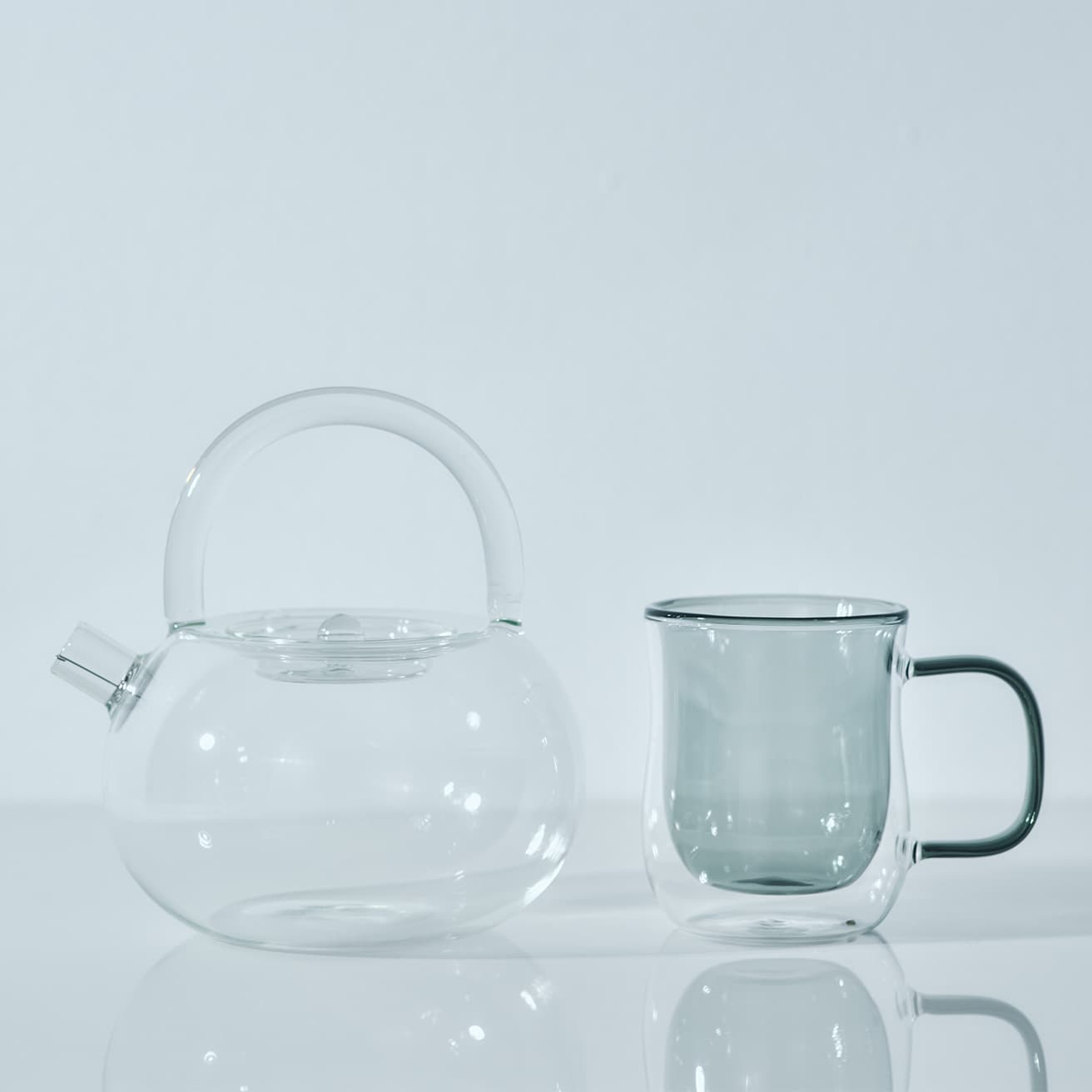〈ポカロティー 〉《透明丸型ティーポット》（耐熱ガラス直火対応 850ml）3,980円。〈ニュイ〉《ダブルウォールグラスマグ グレー》W11.5×D8×H9.5cm（275ml）2,200円。