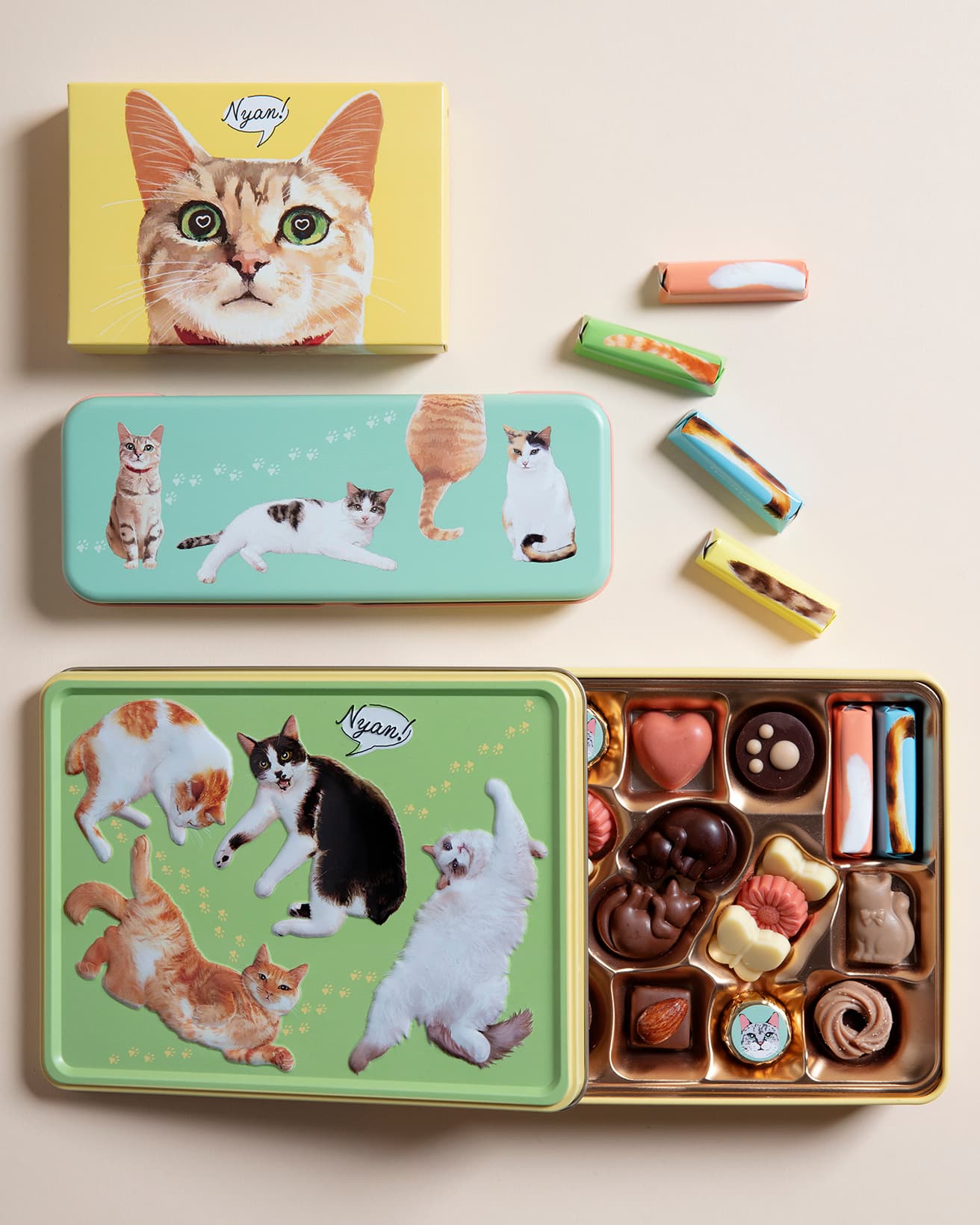 右上／尻尾がモティーフ。チョコクリームとストロベリーの2種のお味。《しっぽ缶》11個入1,080円。下／ネコチャン満載《にゃそーてっどチョコレート》22個入缶1,944円。左上／《にゃそーてっどチョコレート》6個入箱594円。