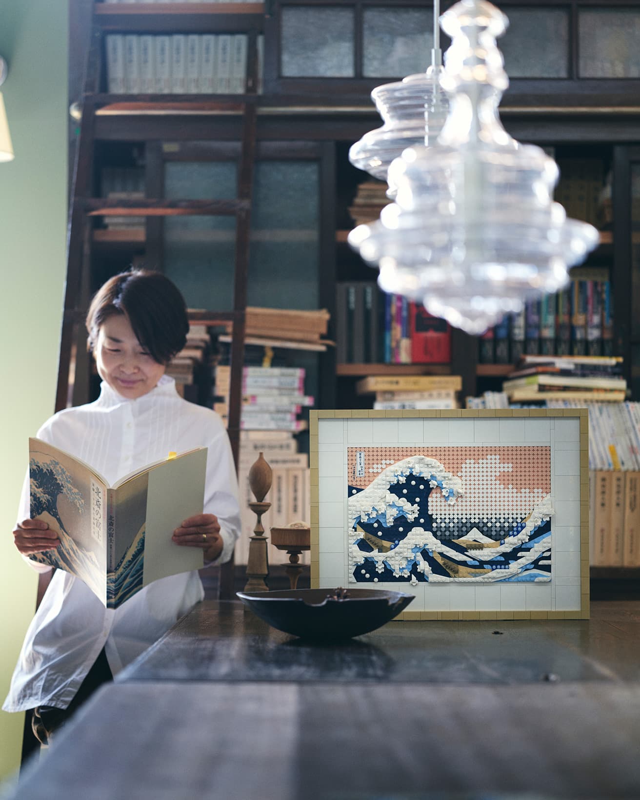 レゴ®️アート 北斎《冨嶽三十六景 神奈川沖浪裏》のそばで、読書を楽しむ橋本さん。今回、レゴ®️アートの制作に挑戦してもらった。