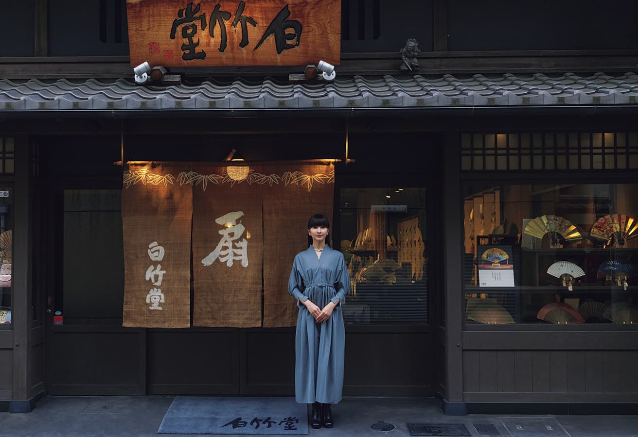 At Hakuchikudo’s flagship shop, in continuous operation since 1718. Kyo-sensu is a style of handheld fan fully constructed with materials and processes performed within the prefectures of Kyoto and Shiga. Our shopkeeper, KASHIYUKA, selects a hand-painted fan, commenting that, “this will go well not only with traditional kimono, but also with everyday Western fashion.”