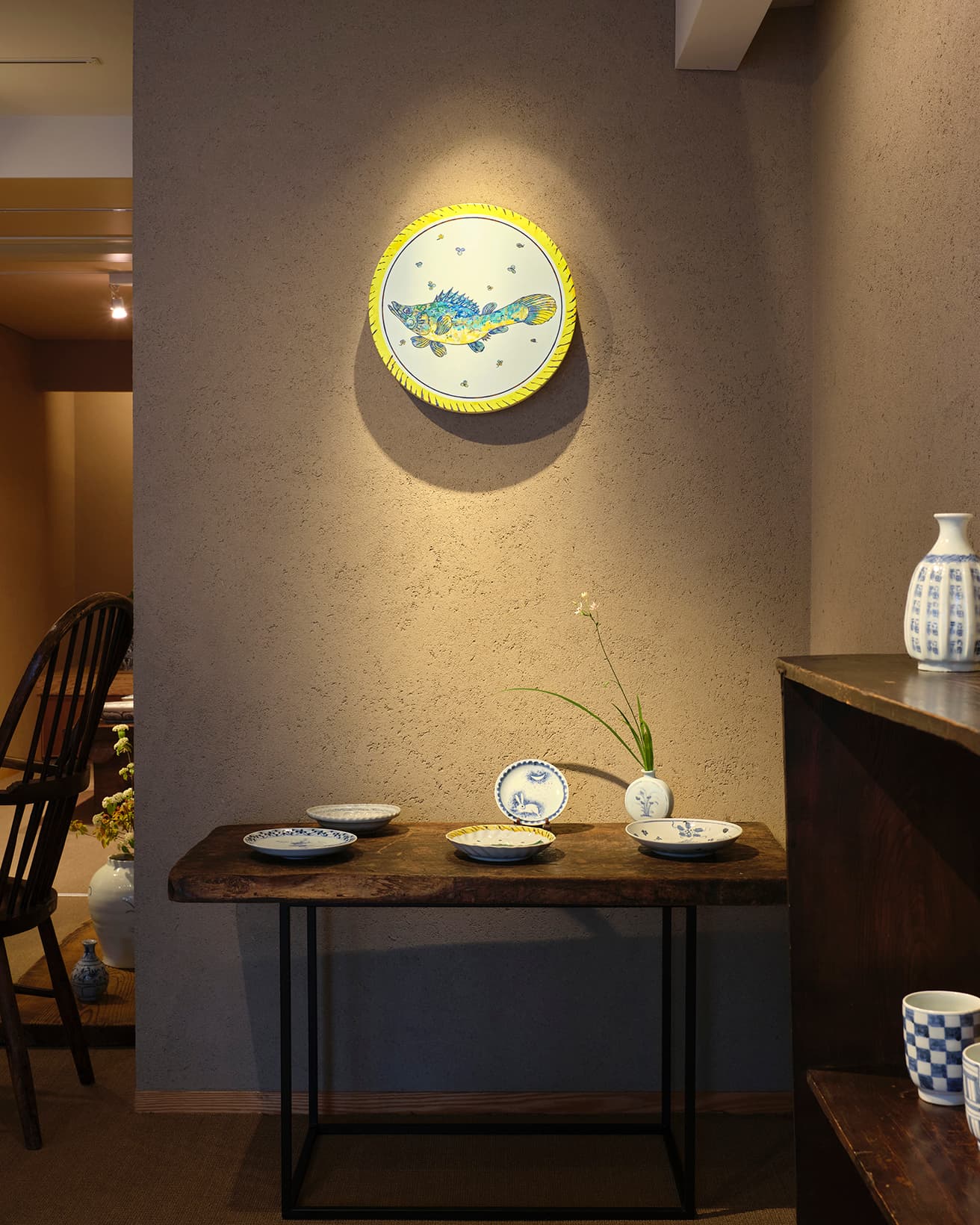 村上隆作品《ケツギョ 交趾風魚文中皿 魯山人 賛》2023 φ400×50mm。右の棚の上《初期伊万里写徳利福字 B》33,000円、棚の中《古染付写市松文湯呑み》16,500円。テーブルの上の中央《初期伊万里写吹墨月兎皿》14,300円など。 
