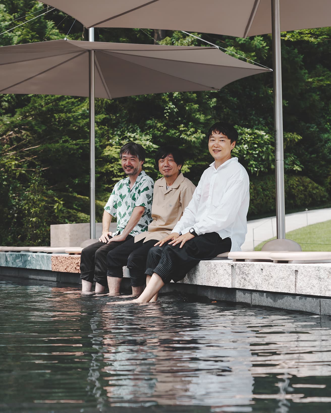 敷地内の源泉を使用した〈森の足湯〉。左から園田慎二、トラフ建築設計事務所の禿真哉と鈴野浩一。