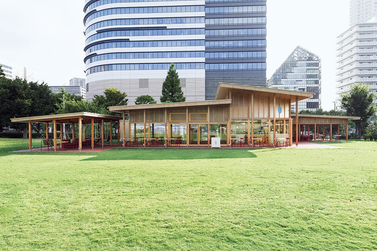 公園と調和し溶け込む、開放感のある外観。半屋外空間には利用シーンに合わせて使えるソファやラウンジチェアの席を配置した。