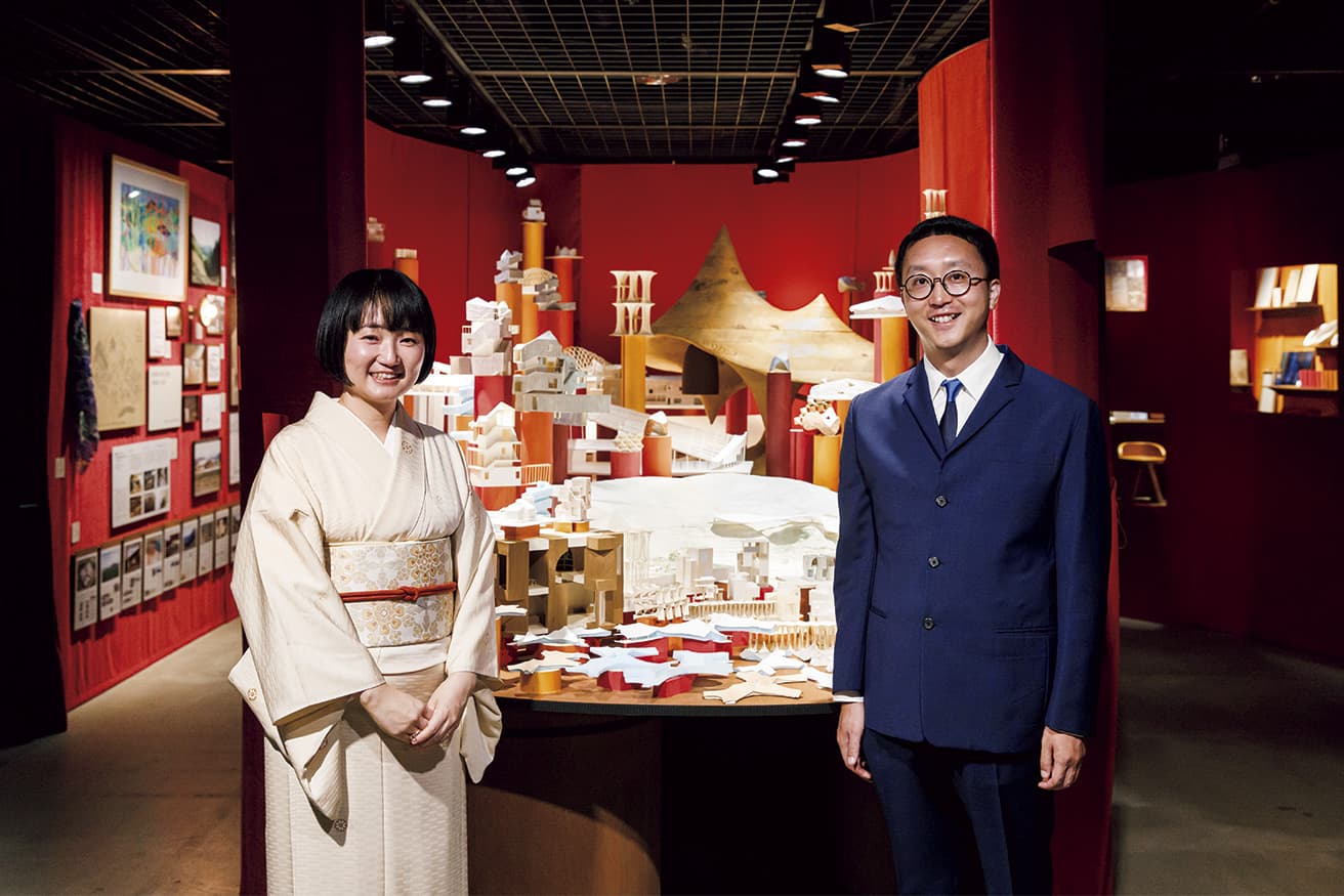 オープラスエイチ　2008年に大西麻貴と百田有希が設立し、共同主宰する設計事務所。2023年に〈シェルターインクルーシブプレイス コパル〉で日本建築学会賞受賞。二人の奥にあるカーテンは本来閉ざされており、のぞき穴から内部を見る仕掛け。
