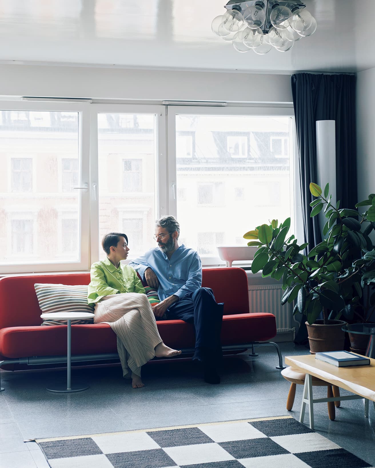 Area：Stockholm / Size：83平米 / Type：Apartment　ジェームス・アーヴィンの赤いソファとサイドテーブルが目を引くリビング。照明はアキッレ・カスティリオーニの《タラクサカム》。