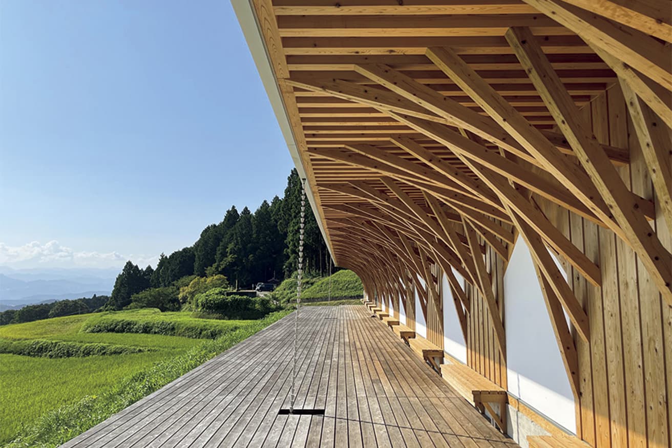 背後の集落の眺望を確保すべく、建物は低く抑えられ、深い軒下は農作業の休憩や眺望の場として開放されている。
