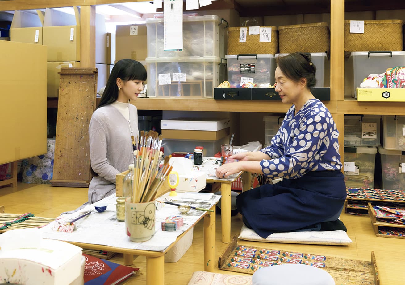 「幸運や金運をかき集める」とされる熊手は、商売繁盛や招福を願う縁起物。七福神が乗り込んだ宝船を表す「宝船熊手」を作る〈よし田〉で、4代目店主の吉田京子さんと。「小さな絵札まで全部手描き！」とかしゆか店主。