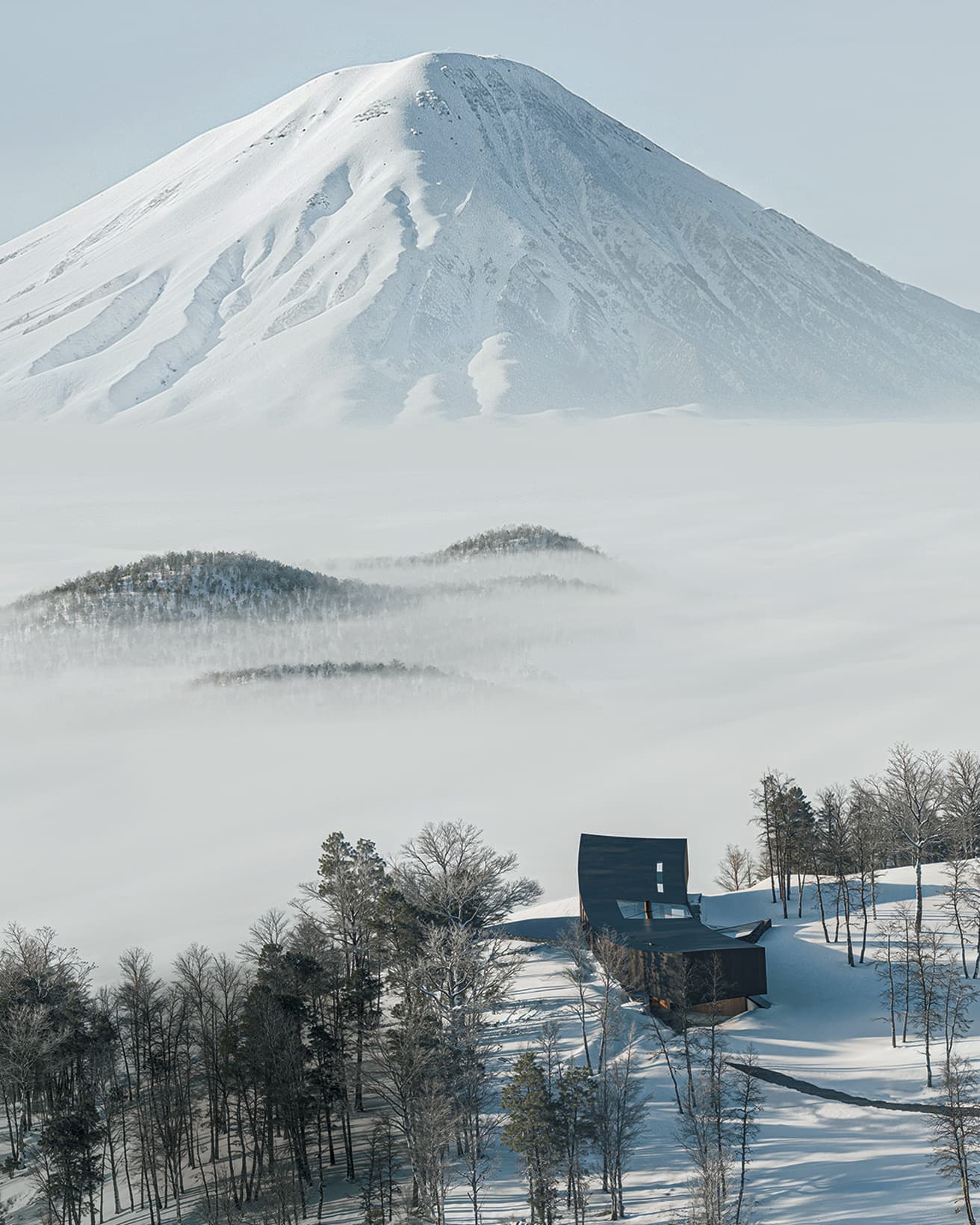 蝦夷富士とも呼ばれる羊蹄山をすぐ目の前に望む、唯一無二のロケーション。山頂の地形を反転させた弓形の地上部分にはレベルの異なる居住スペースがあり、それと交差するように配された地中部分にジムやサウナが入る。
