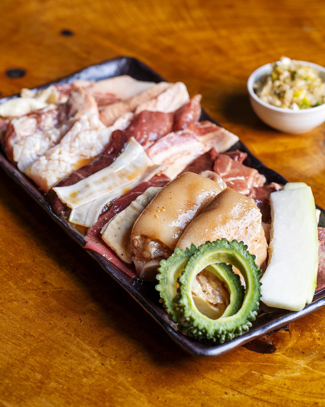 《肉全盛り》1人前3,350円。写真は2人前。左手前から豚足、テッポウ、コブクロ、レバー、吟醸ホルモン、ハラミ、トンチャン、右手前の野菜、ナーベラーの下にトンスジ、豚舌、コリコリ、かしら、おっぱい、ハツ、カルビ、ヒレロース、豚トロ、肩ロース。ロースなどは塩、ホルモンはタレで。自家製のネギ薬味と。
