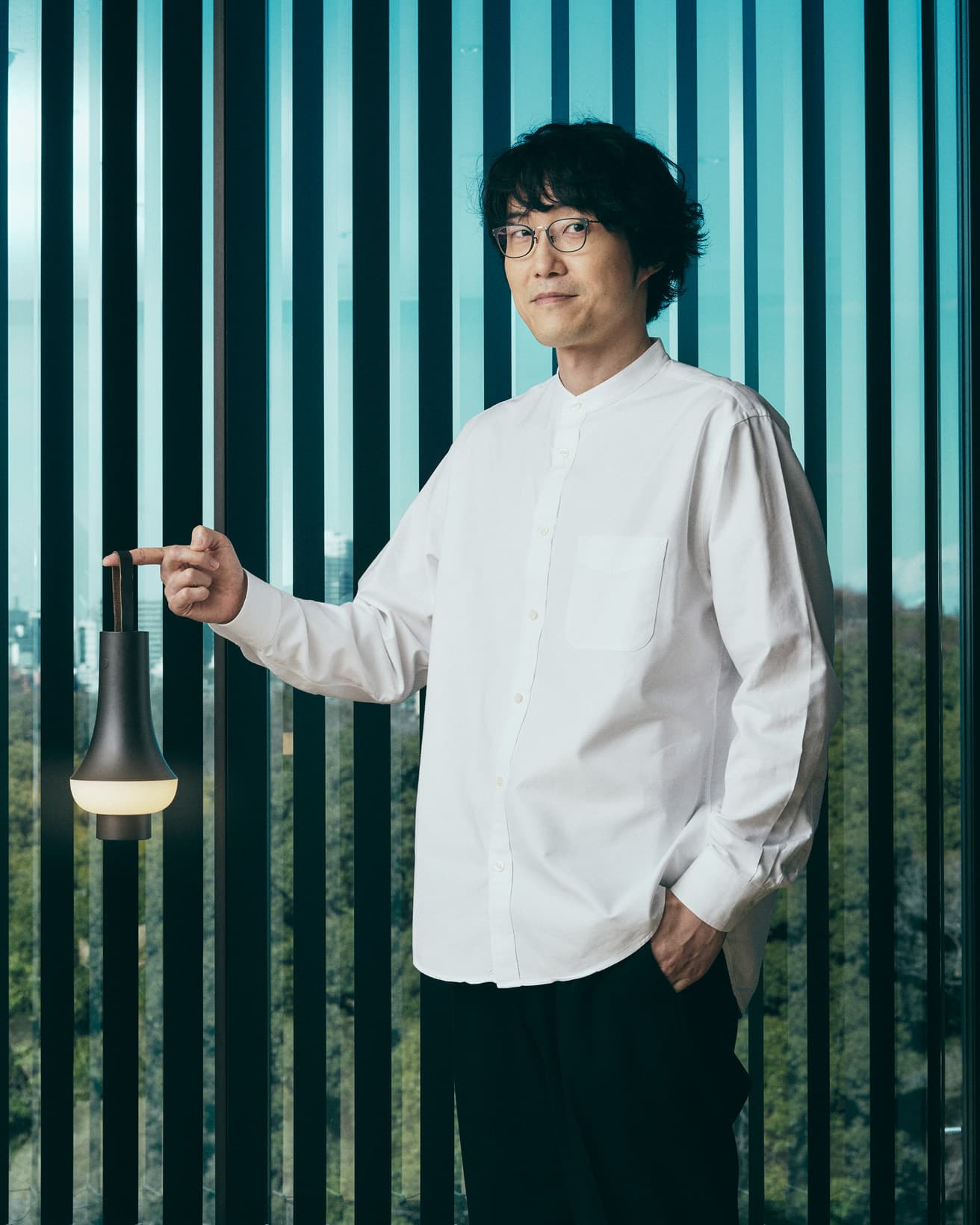 《Tomoshi》を手にする佐藤オオキ。ストラップはすっと手を伸ばし、無意識に持ち上げたくなる形をしている。