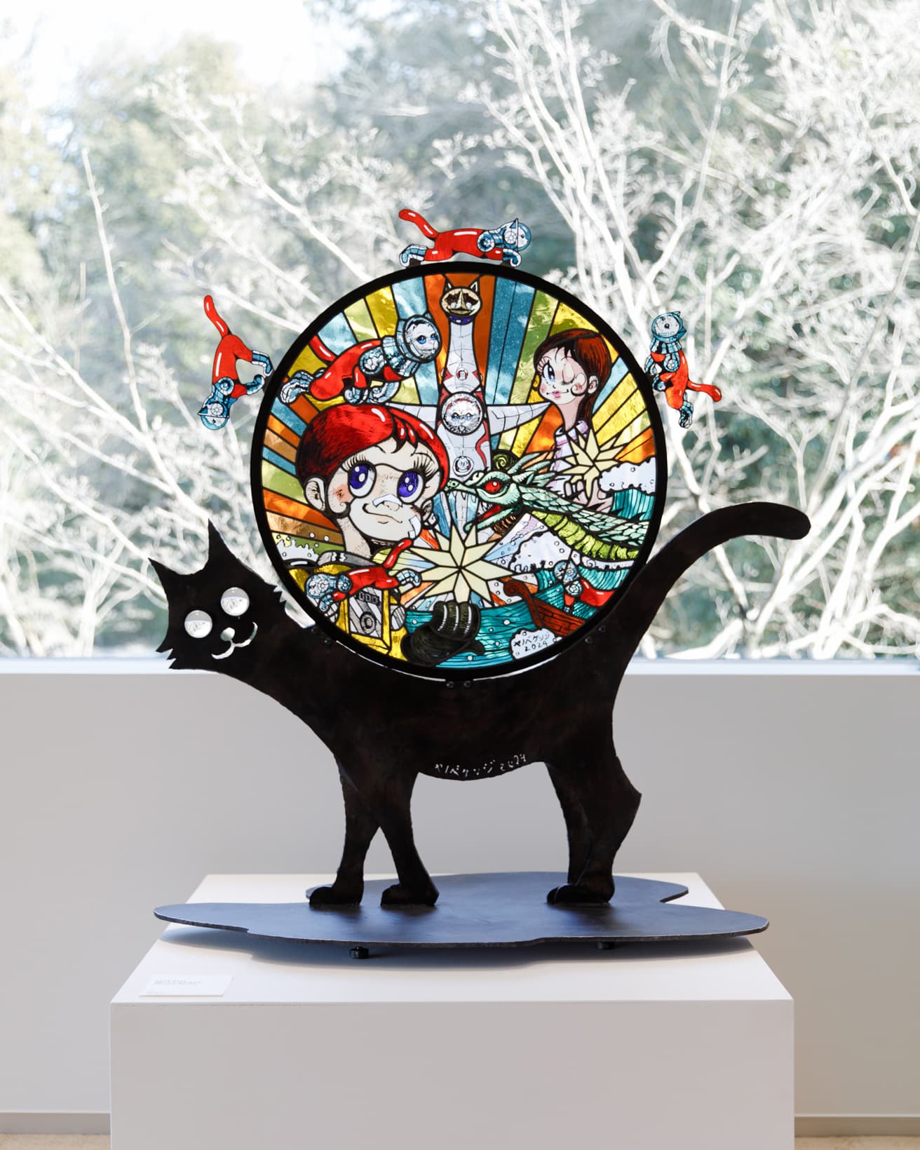 《SHIP’S CAT(Journey of Life)》（2024）。大阪モノレール大阪空港駅に設置された大型ステンドグラス作品《Journy of Life》（2024）の絵画がステンレス彫刻のネコチャン土台に鎮座。