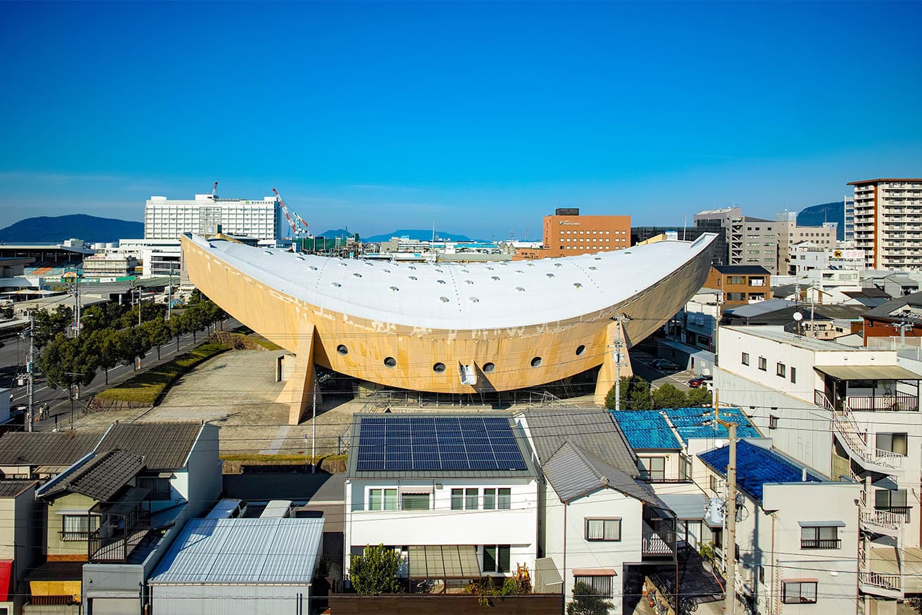 南から見た体育館。日本刀の反りをイメージしたフォルムが美しい。側面の中央付近に巨大なガーゴイルも見える。