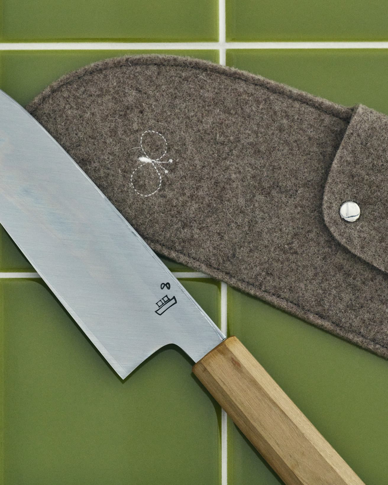 〈ミナ ペルホネン〉の代表的モチーフをアレンジ。刃の裏側には釜浅商店のロゴとともに刻印。そしてフェルトケースにもステッチが施されている。