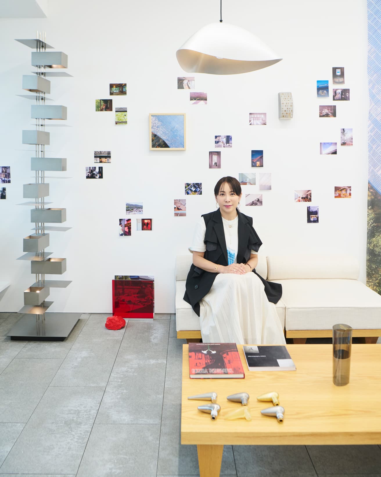 自身が手がけたソファに座る永山祐子。壁に貼った写真群にはプレゼンの様子を撮影した貴重なスナップも。