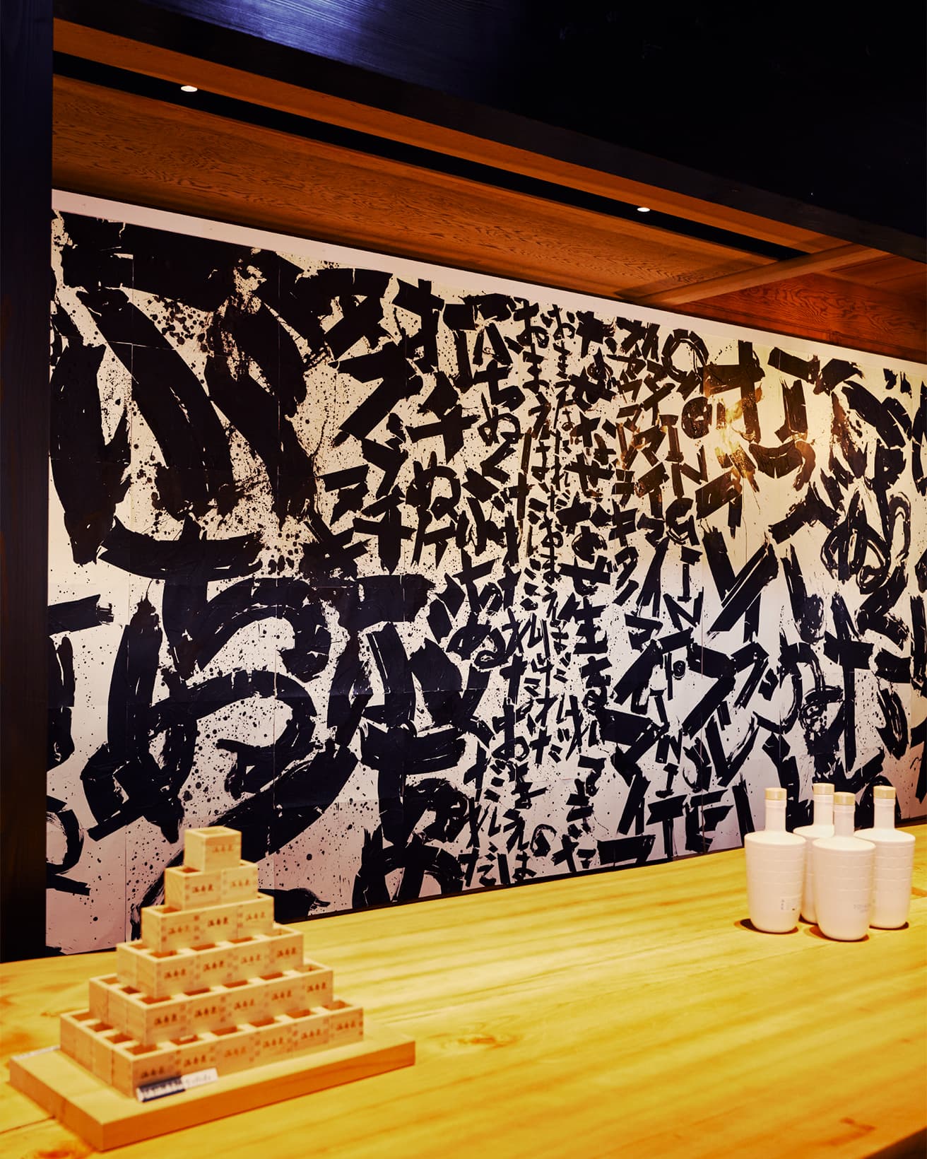 日本酒バー〈桝田酒造店 沙石〉の壁には柿沼康二の書《ぶちぬく》が展示されている。