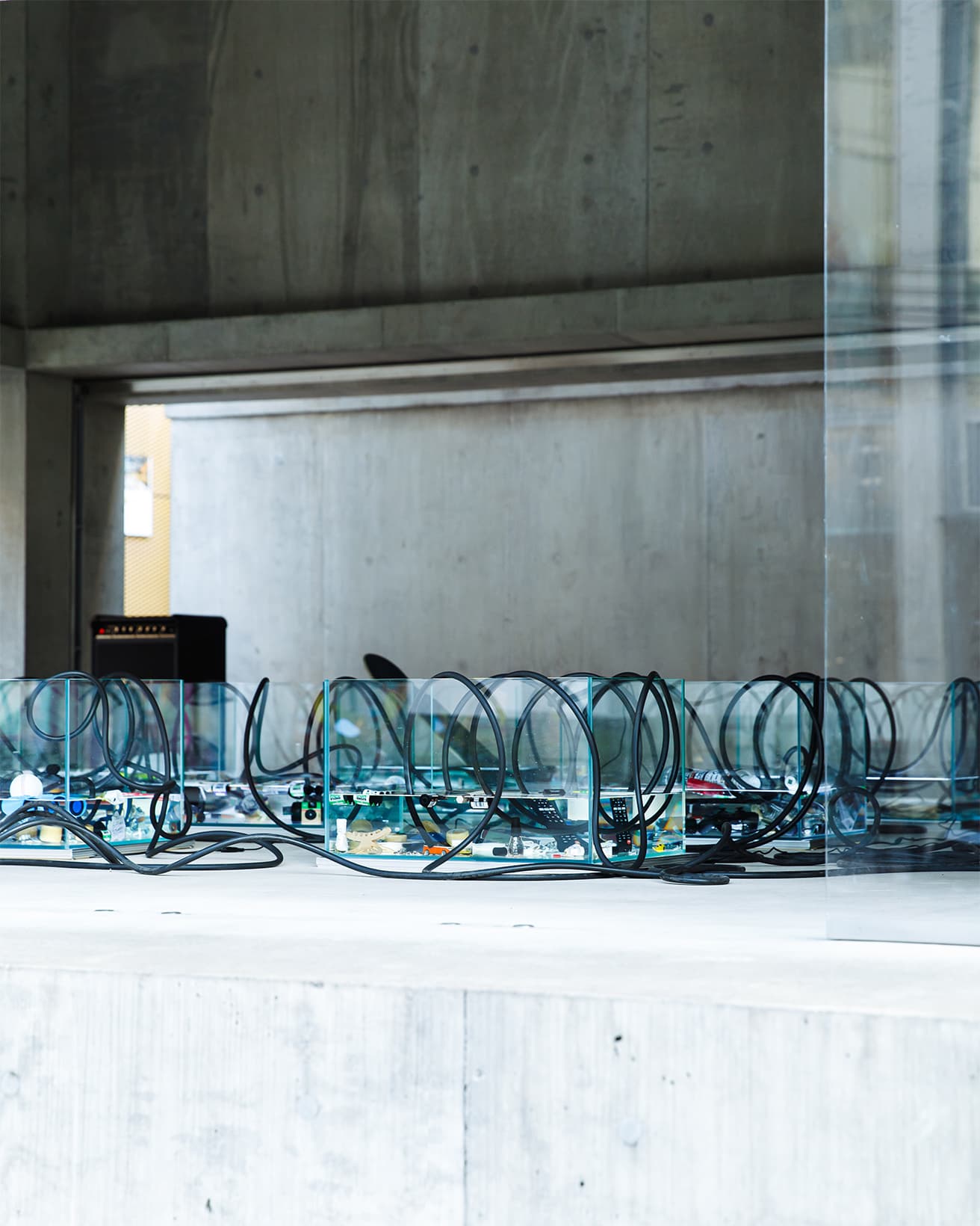 日用品が沈む水槽のなかにアンプから伸びるコードが浸かる。