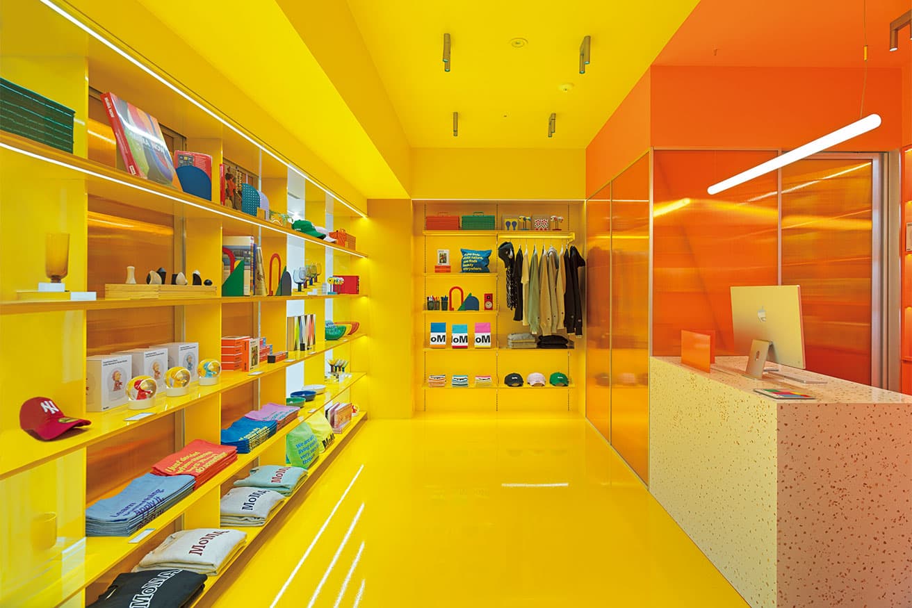 淡いグレーの思索的な書籍ホールから光沢ある暖色が基調のデザインストアへ雰囲気を変える色使いが卓越。