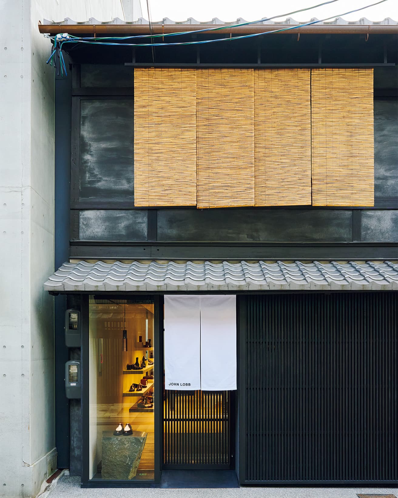 ファサードの格子や建具はヒノキを染色して既存の木材と色を合わせた。ウィンドウのディスプレイ台には、イサム・ノグチも多用した宮城・大倉山スタジオの伊達冠石を採用。 
