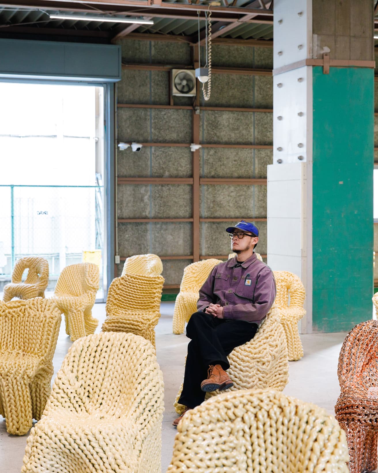 《GHOST IN THE SHELL》の椅子に座るイ・カンホ。展示されている《GHOST IN THE SHELL》の椅子は実際に座ることができる（一部を除く）。