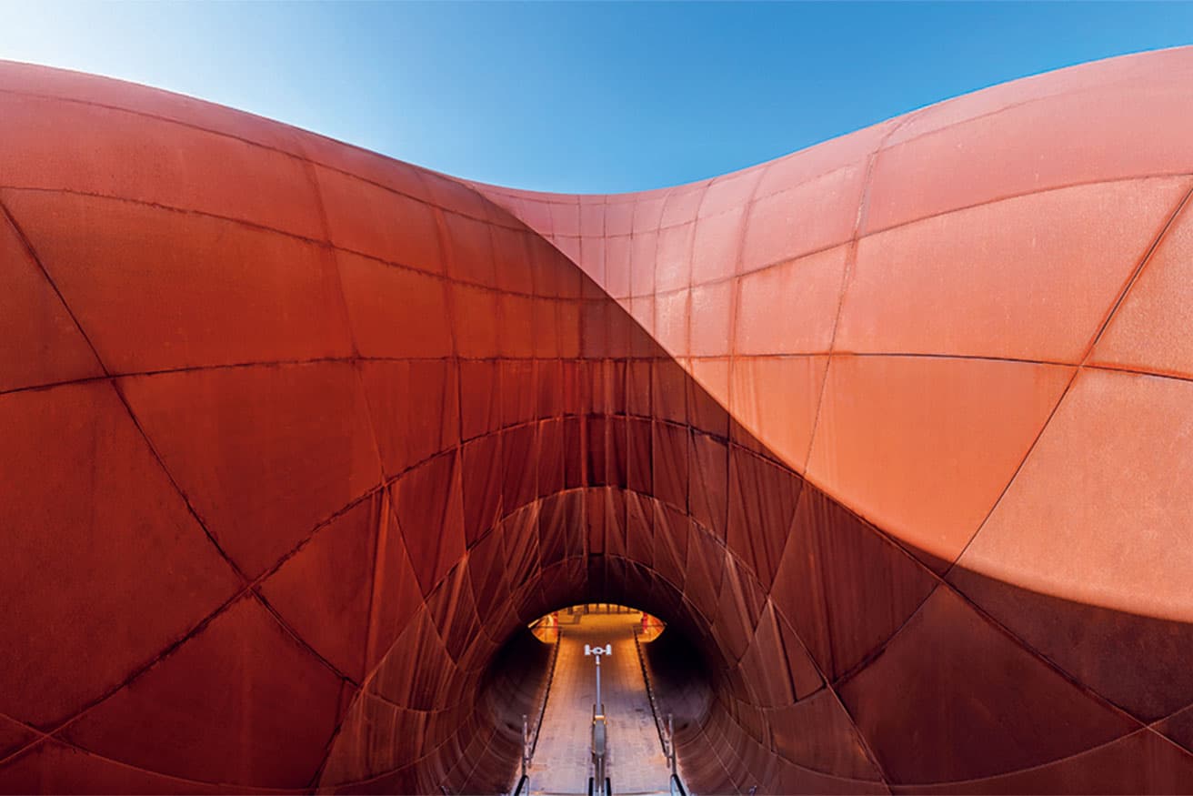 耐候性の高いコルテン鋼で作られている、膨れ上がったようなフォルムの入口。