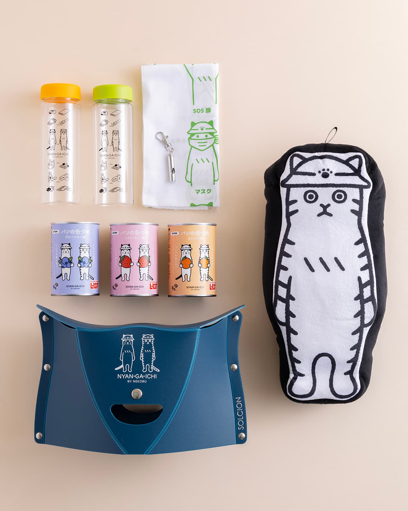 防災グッズブランド《NYAN GA ICHI》のニャイテム。左上から時計回りに《もしもに備えて手軽に持ち歩き 防災ボトル》各1,536円。《もしもに備える防災てぬぐい》823円。《もしもの時にピッー！携帯ホイッスルチャームの会》1,755円。《そばにいるよ ぬいぐるみブランケット》もしもくんver. 5,270円、《ペタンコになってとっても軽い 折りたたみいすの会》3,403円。《ローリングストックにぴったり　甘くてふわふわパンの缶づめ》各1,508円。販売価格の一部は飼い主のいない動物の保護と里親探し活動、野良ネコチャンの過剰繁殖防止活動、災害時の動物保護活動などに活用されるそでございます。