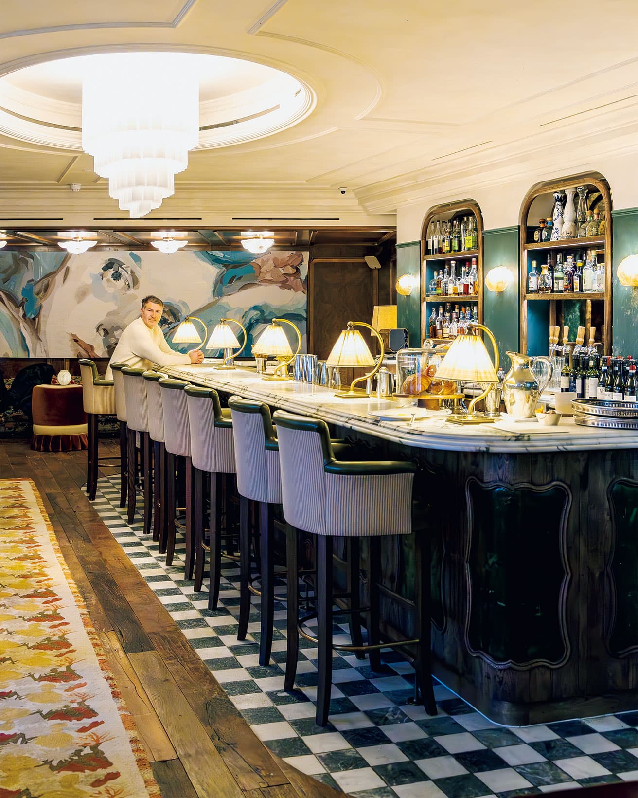〈ソーホーミューズハウス〉。マーブル仕上げのバーでくつろぐCEOのアンドリュー・カーニー。クラシックな内装にモダンなシャンデリアが、時をつなぐムードを醸す。