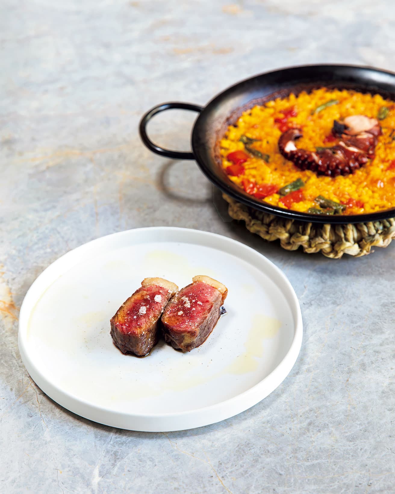 タコのパエリア（写真の料理は9,900円のディナーコースの一例）、北海道産 牛サーロインの薪火焼き。