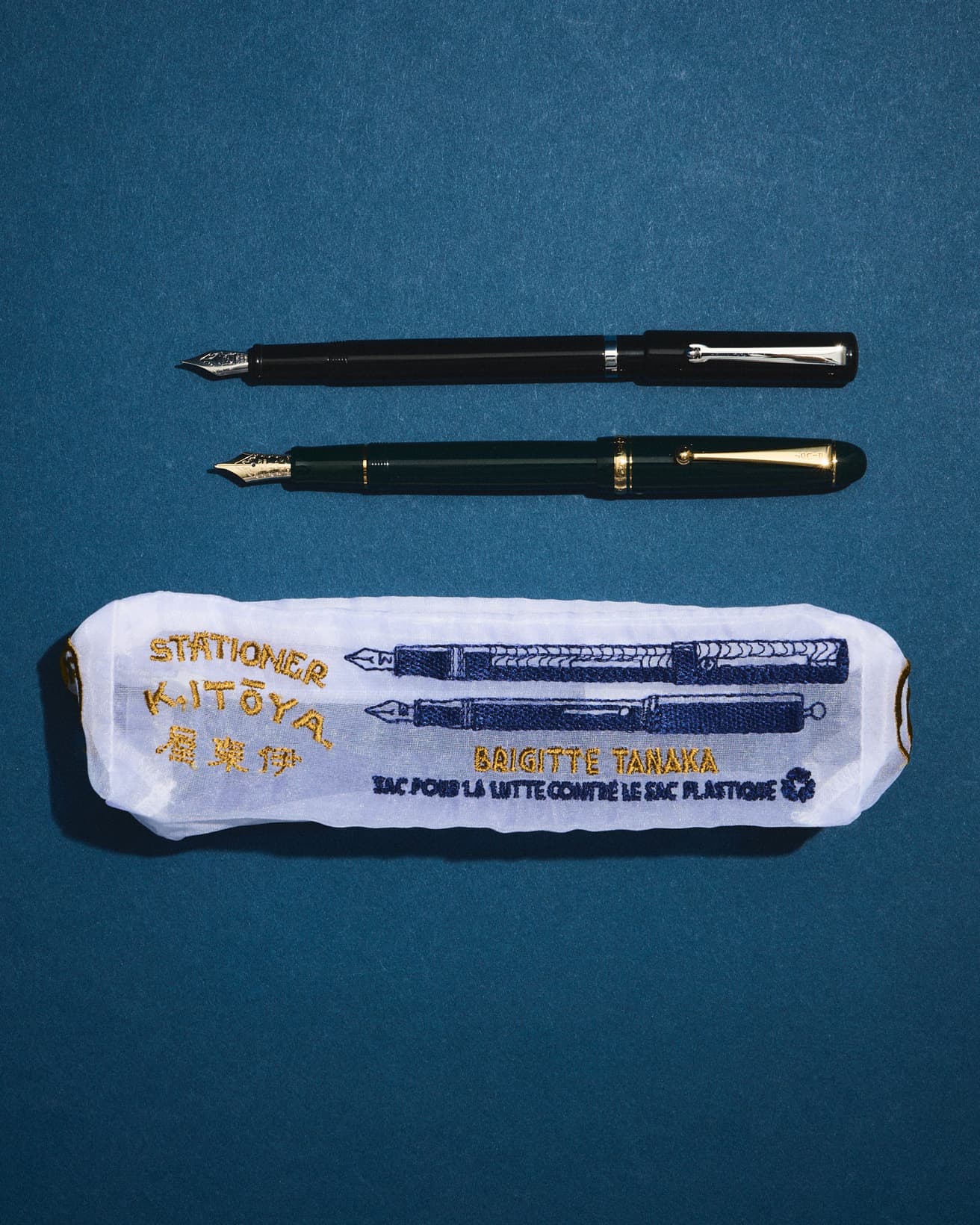 ポーチには、商品目録に掲載された万年筆の図案を刺繍。側面にも、昔の伊東屋ロゴがあしらわれている。オーガンジーポーチに添えた万年筆（上）〈伊東屋〉オリジナル《マイティ》7,700円、（下）PILOT《カスタム74》22,000円。●銀座 伊東屋　本店 TEL 03 3561 8311。