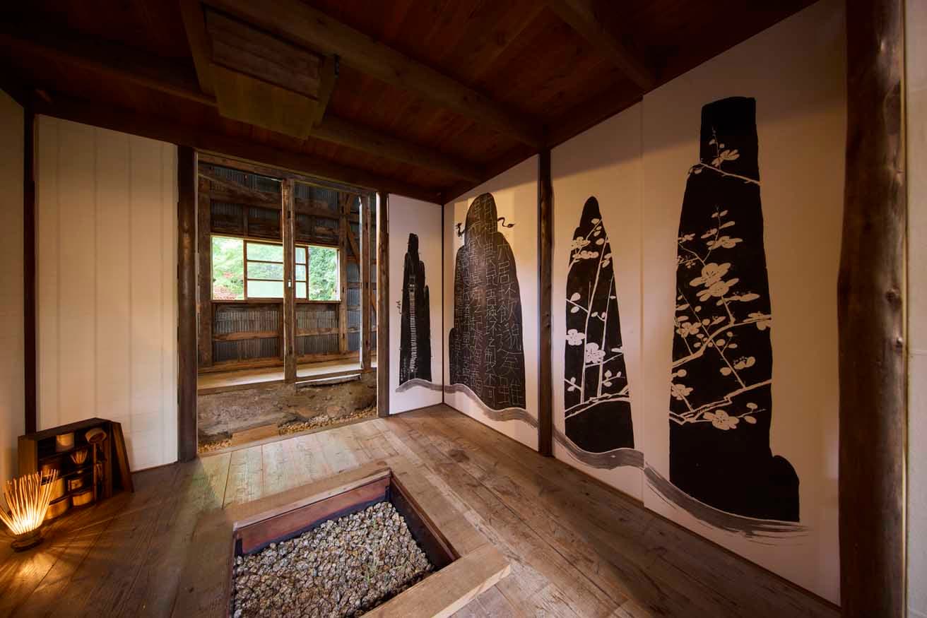 三浦史朗＋宴KAIプロジェクトの展⽰⾵景。壁に上出惠悟の水墨画《夢の香》が描かれている。