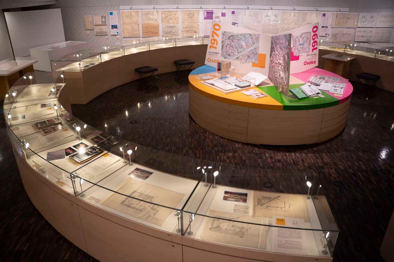 〈国立近現代建築資料館〉の特徴的な円環状のケース、ここに大屋根リング周辺の写真が飾られる（写真は、2025年開催の『日本の万国博覧会 1979-2005』の展示状況）。