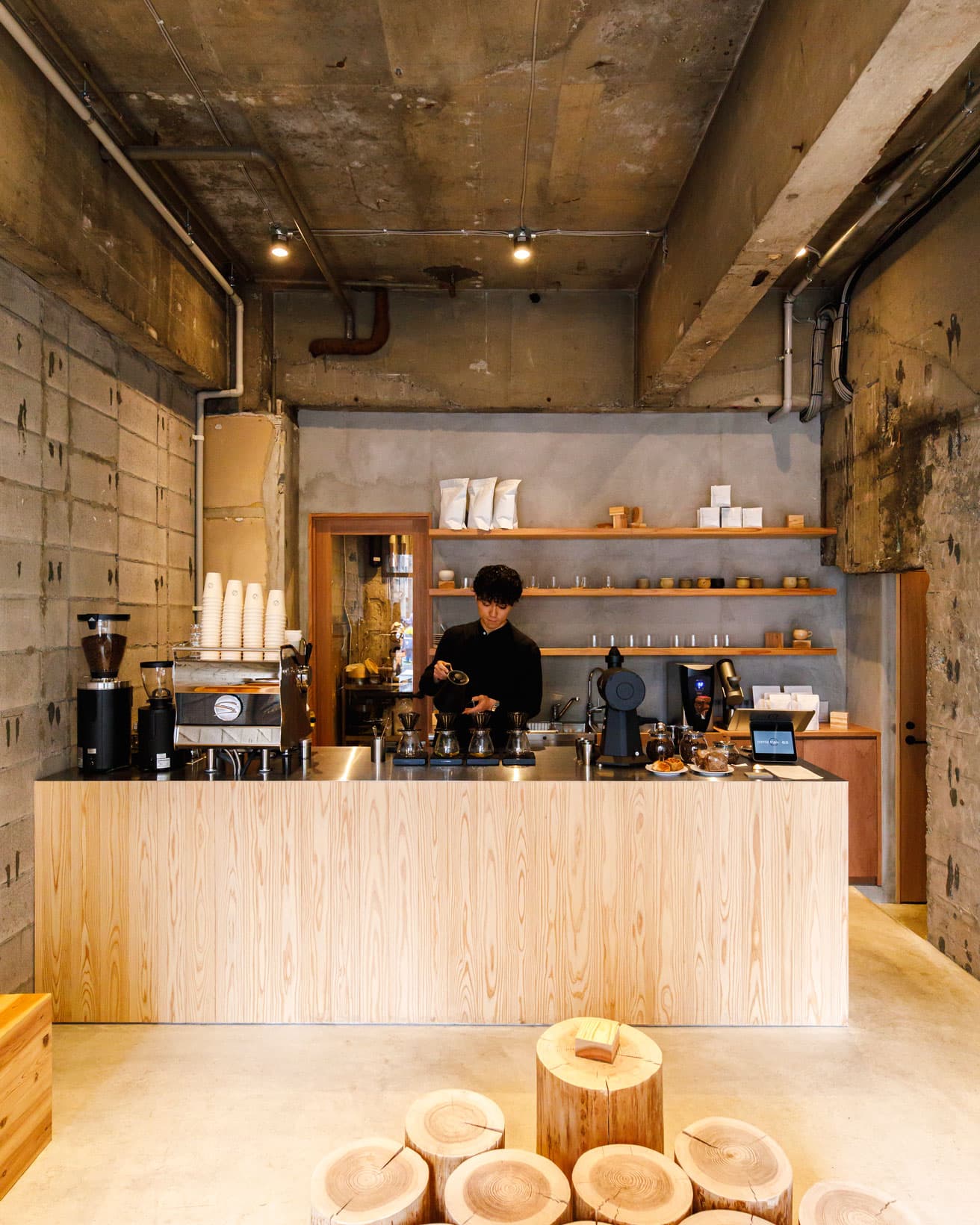 剥き出しのコンクリートと杉の暖かみが調和する店内。無垢の丸太に腰掛けて味わうコーヒーは絶品だ。