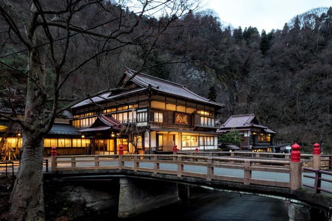 会津東山温泉郷を流れる湯川にかかる東橋越しに見る〈向瀧〉。森を背景に優雅な建築がより美しく浮かび上がる。