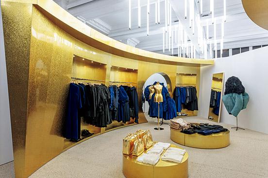 川久保玲デザインの、ゴールドのパネルと照明にも注目の〈コム デ ギャルソン〉の売り場。