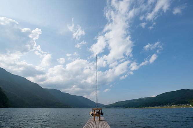 五十嵐靖晃《雲結い》（くもゆい）。垂直に伸びる藍染めの組紐が湖と空をつなぐ。この世とあの世を結ぶようにも見える。　photo_Tsuyoshi Hongo