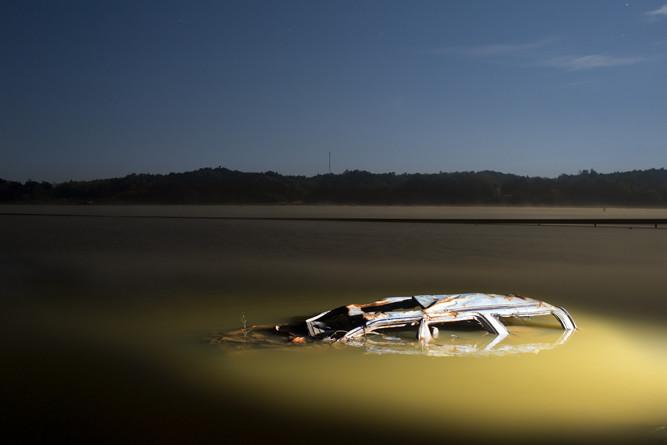 夜間、強いフラッシュをあてて撮った作品シリーズ「光影」（2011-2013）より。水面に浮かび上がった自動車の瓦礫。　© Carlos Ayesta + Guillaume Bression